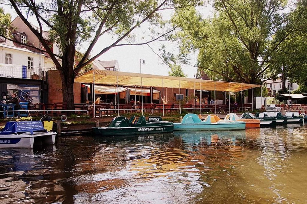 Bunte Tretboote am Steg unter Bäumen