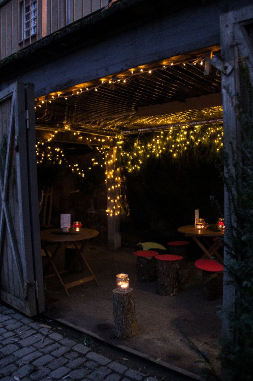 Überdachter Sitzbereich mit Lichterketten und Kerzenlicht bei Nacht