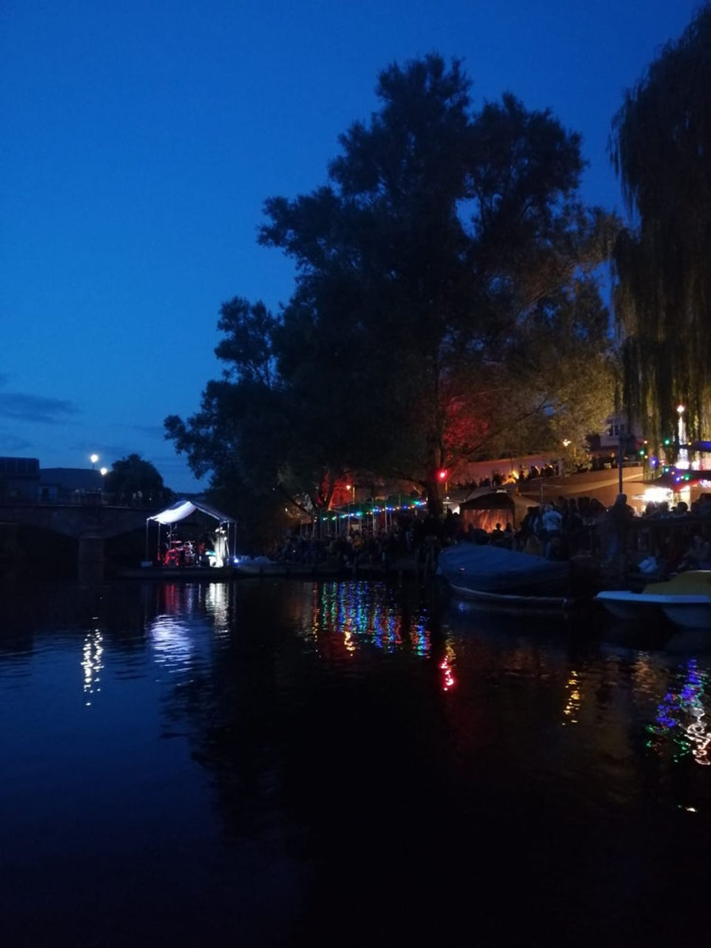 Blick vom Fluss auf die schwimmende Bühne mit bunten Lichtreflexionen