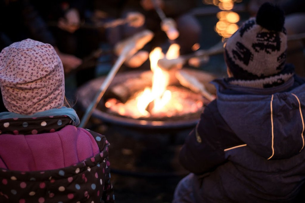 Kinder backen Stockbrot am Lagerfeuer