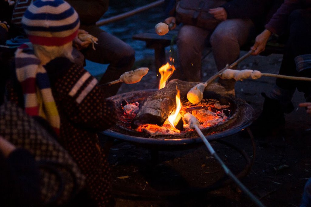 Familien rösten gemeinsam Stockbrot am Lagerfeuer
